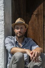 Christoph Huber vor dem Eingang einer Hütte sitzend